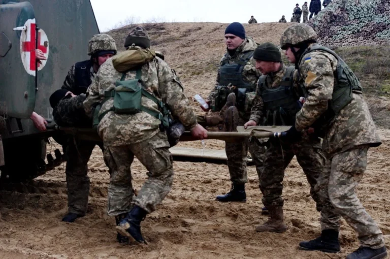 Українські військові евакуюють пораненого на носилках до санітарки на фронті