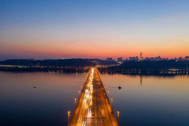 Аерознімок аварійного мосту Патона в Києві на заході сонця з ілюмінацією.