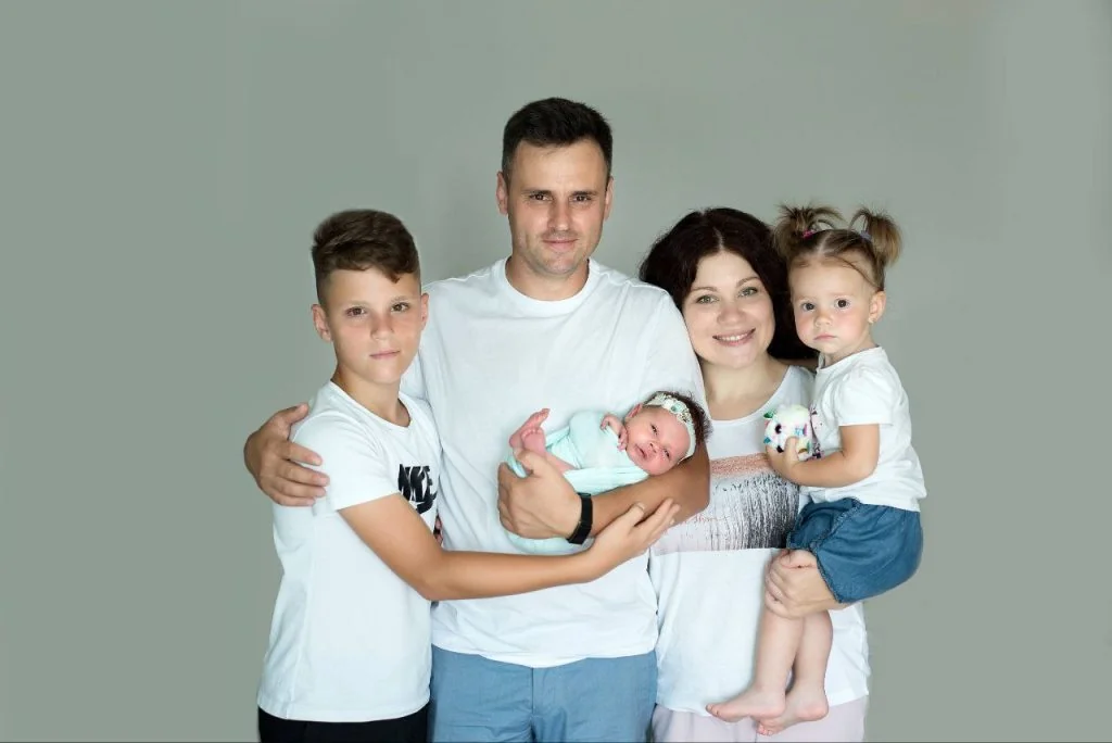 Емілі Каллум з чоловіком і трьома дітьми тримає немовля на руках