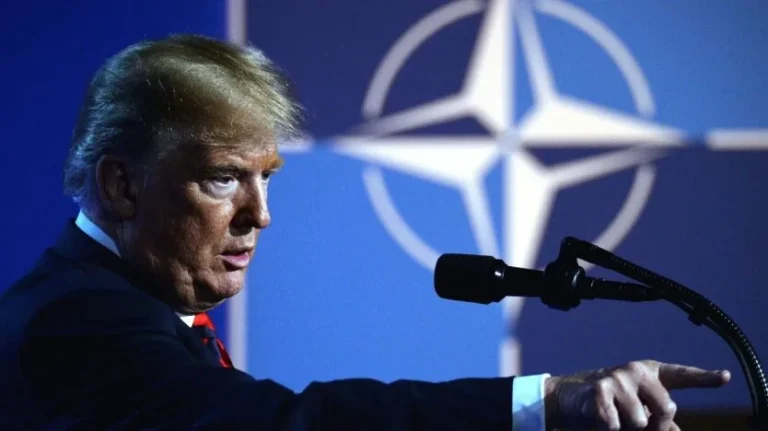 Дональд Трамп виступає за трибуною на тлі логотипу НАТО