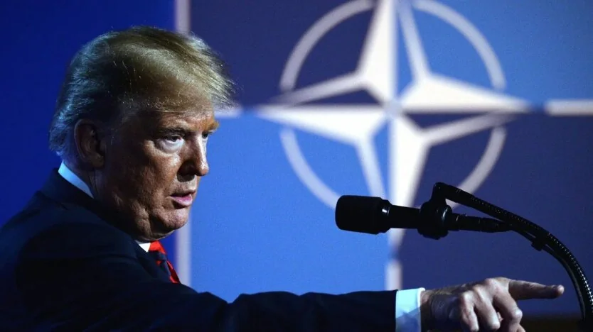 Дональд Трамп виступає за трибуною на тлі логотипу НАТО