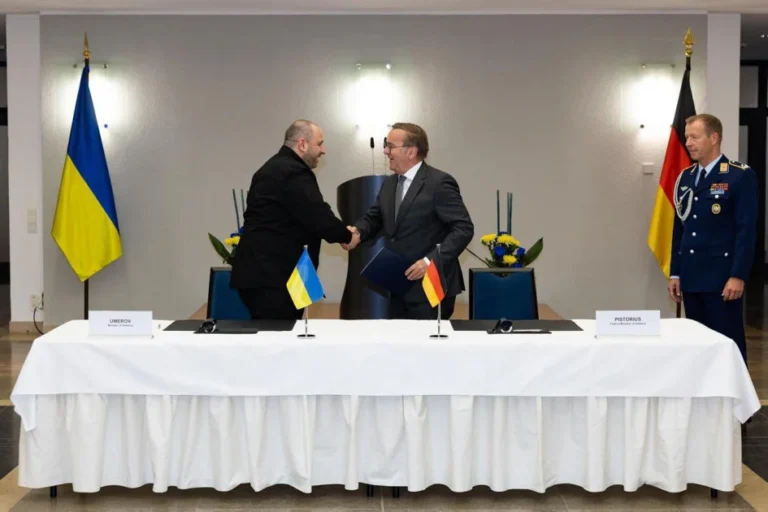 Борис Руге, эксперт НАТО, пожимает руку дипломату перед флагами Украины и Германии
