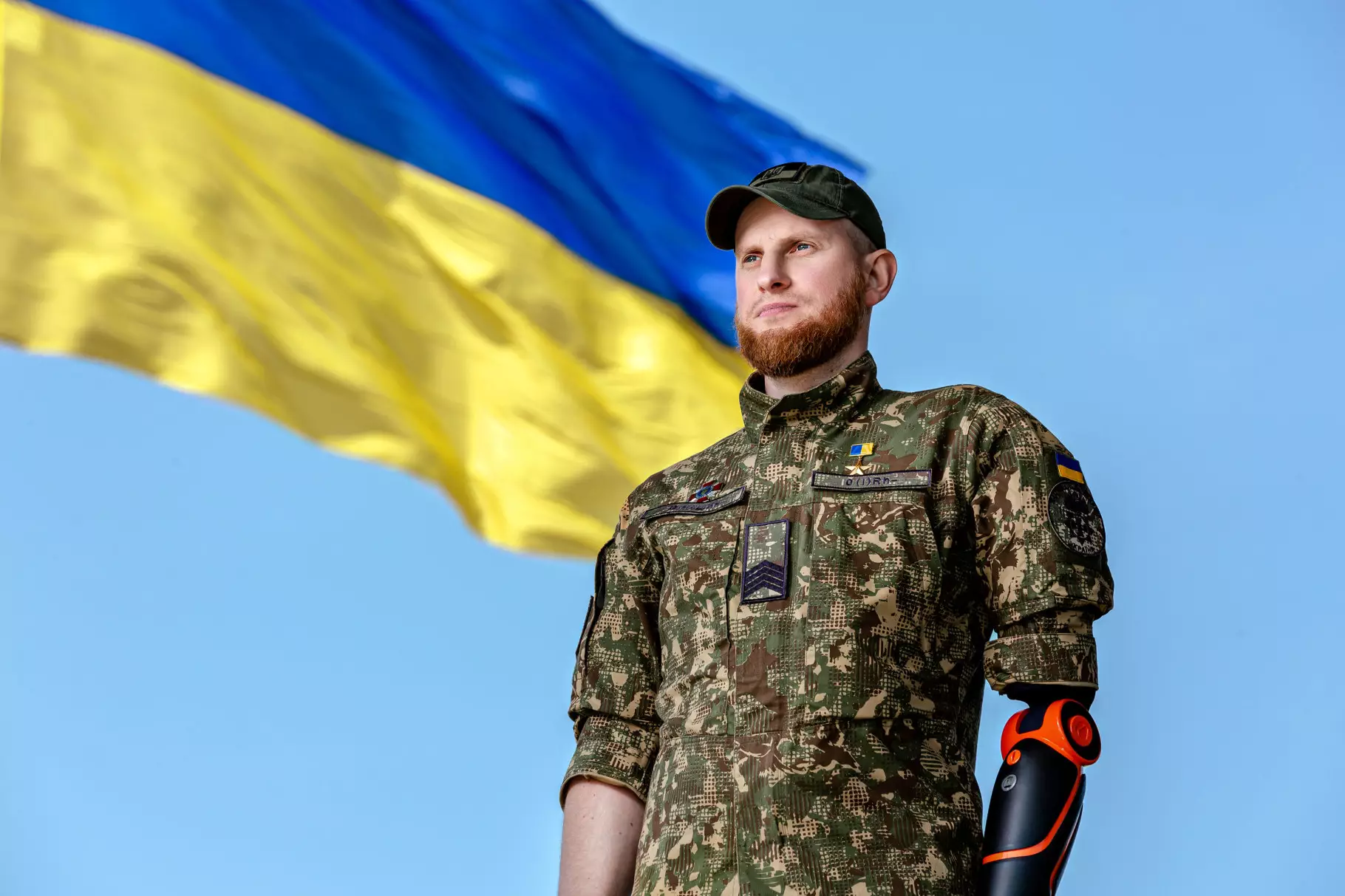 Ярослав Грубич з протезом на правій руці в камуфляжі на тлі українського прапора