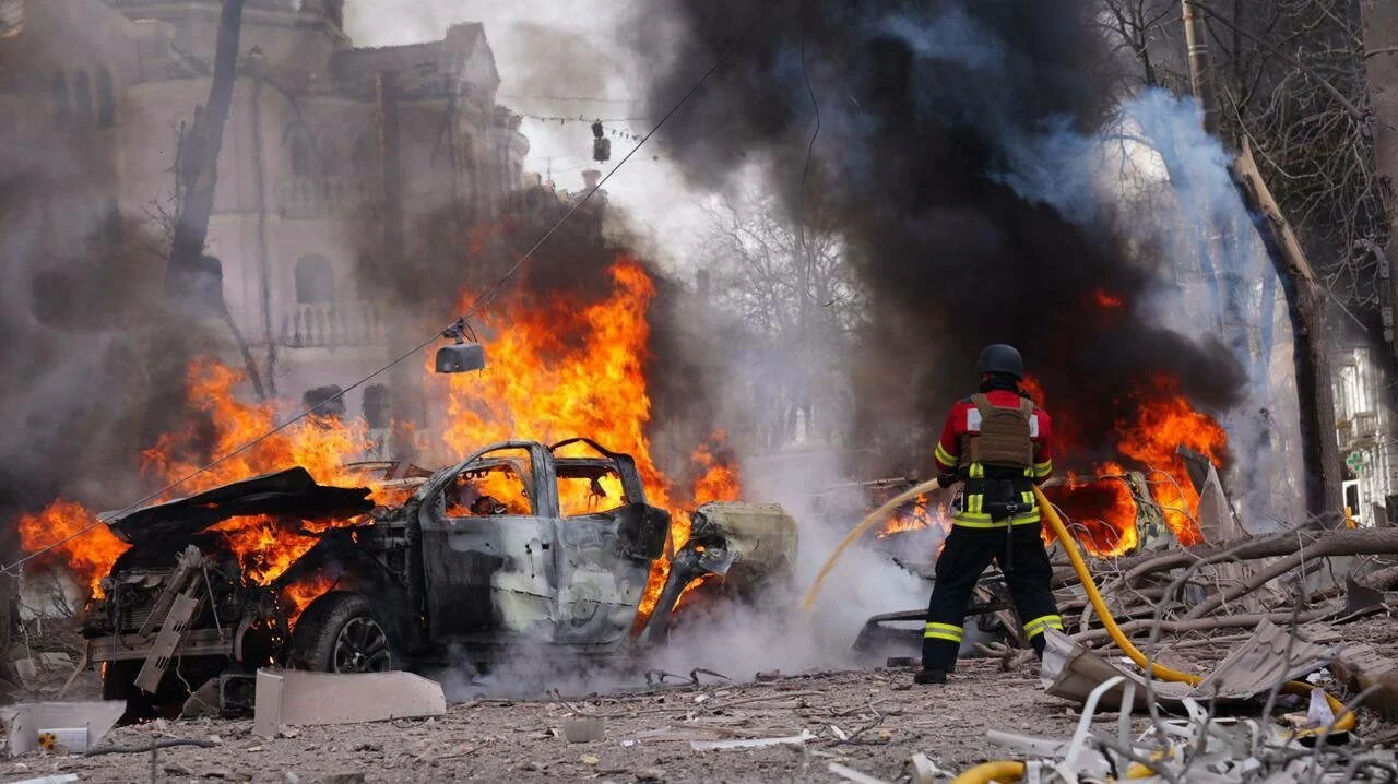Рятувальник гасить палаючий автомобіль після ракетного удару по Дергачах
