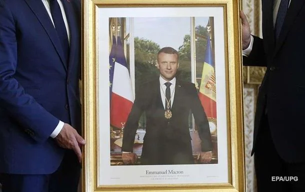 Портрет Еммануеля Макрона в золотій рамі з прапорами Франції