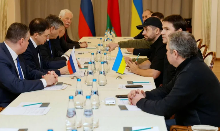 Переговори делегацій Росії та України за столом з прапорами
