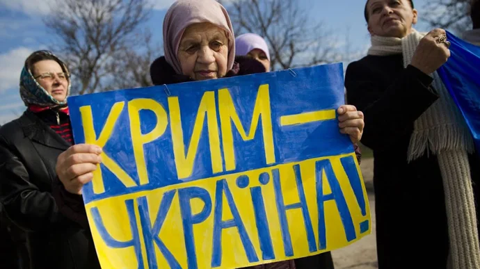 Жінки тримають плакат Крим — Україна на акції проти окупації півострова