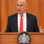 Міністр оборони Британії Джон Гілі виступає за трибуною з гербом