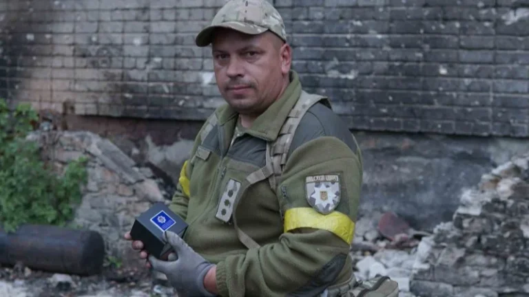 Військовослужбовець Нацгвардії України тримає пристрій на тлі зруйнованої стіни