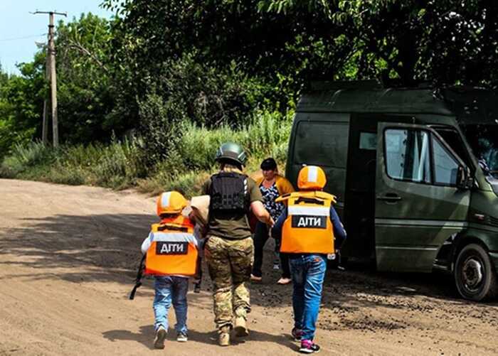 Волонтери евакуюють дітей у жилетах ДІТИ до транспорту на Харківщині