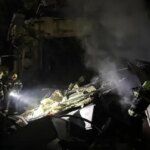 Рятувальники з ліхтарями працюють на місці пожежі та руйнувань після балістичного удару Росії по Києву вночі 19 липня
