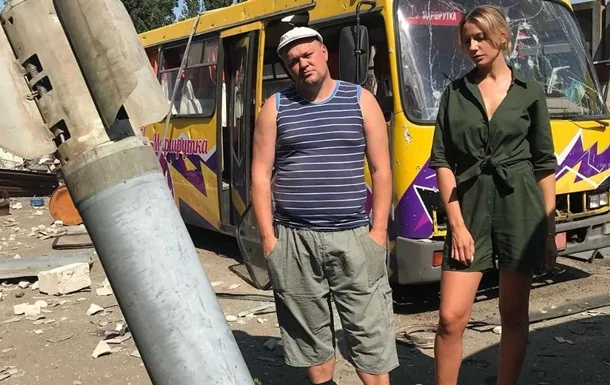 Леся Нікітюк біля пошкодженого автобуса зі слоганом «Слава Україні» під час війни