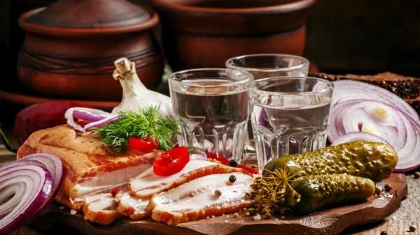 Закуска до горілки з мясом, огірком, цибулею та часником на дошці