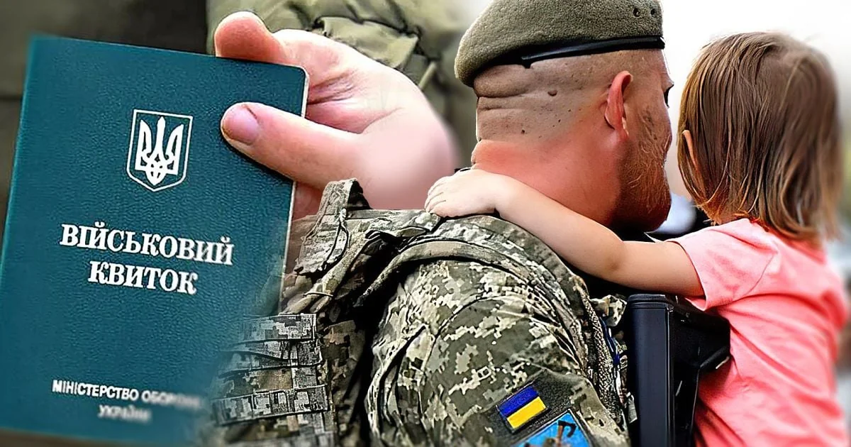 Батько-одинак у формі тримає військовий квиток поряд з донькою