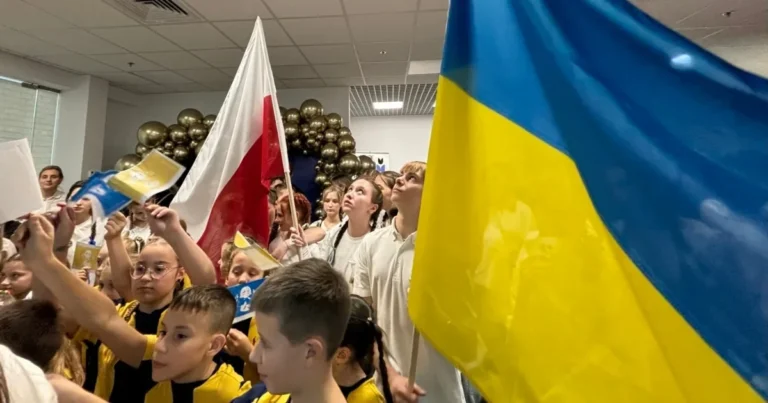 Українські школярі в Польщі з прапорами України та Польщі на шкільному заході
