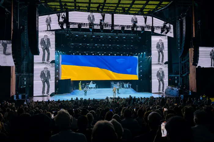 Род Стюарт на сцені концерту з великим українським прапором на підтримку України