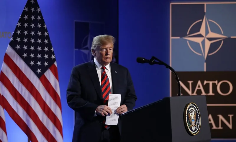Дональд Трамп на саміті НАТО з прапором США та логотипом альянсу