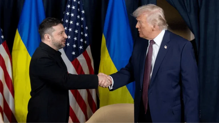 Володимир Зеленський і Дональд Трамп тиснуть руки на тлі прапорів України та США