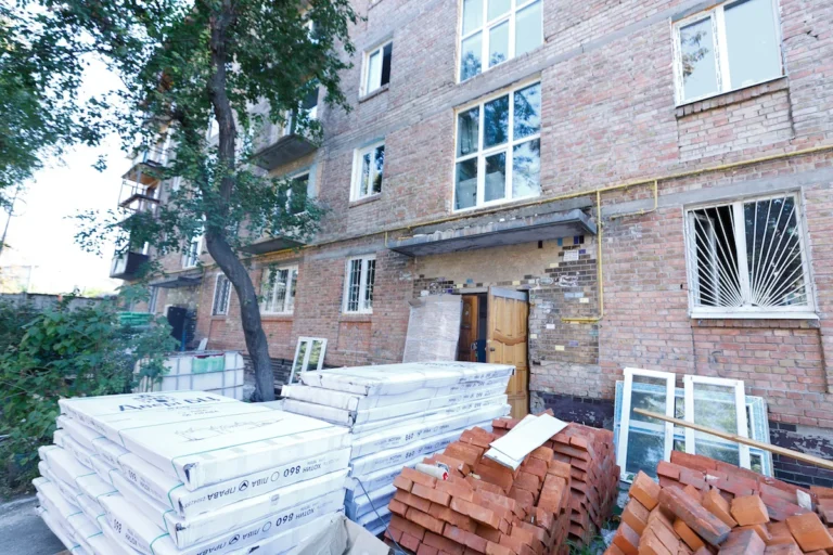Відновлений пятиповерховий будинок на Сирці з будівельними матеріалами після обстрілу