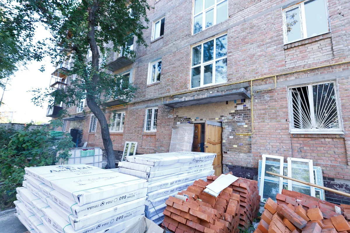 Відновлений пятиповерховий будинок на Сирці з будівельними матеріалами після обстрілу