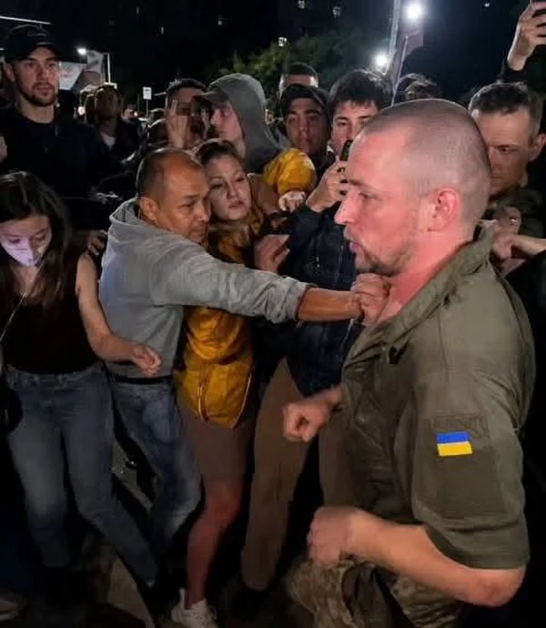 Військовослужбовець у формі з прапором України під час сутички з натовпом у Затоці