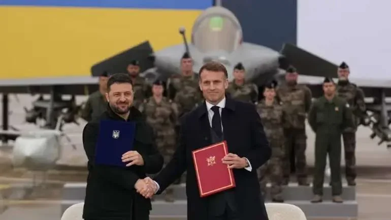 Зеленський і Макрон з документами на тлі винищувача Rafale під час угоди з Францією