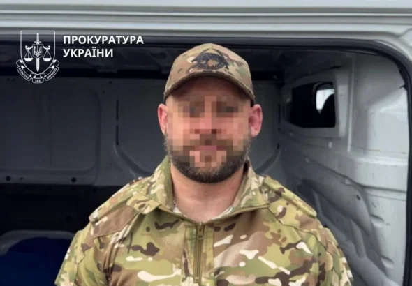 Чоловік у камуфляжі з пікселізованим обличчям біля відкритого білого фургона