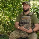 Бойовий медик у камуфляжі та бронежилеті сидить у лісі на Донеччині