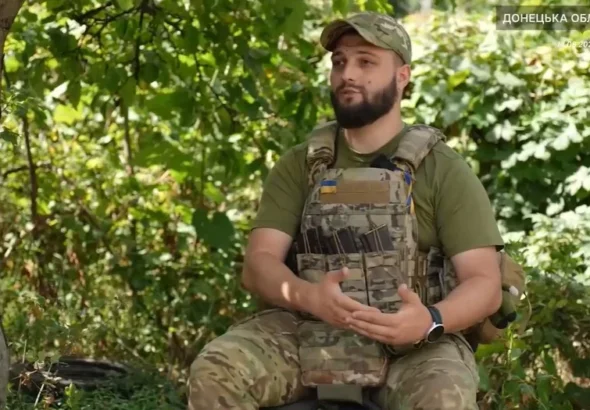 Бойовий медик у камуфляжі та бронежилеті сидить у лісі на Донеччині