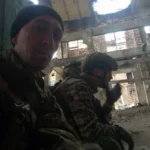 Військовий у чорній шапці на селфі з побратимами в зруйнованій будівлі