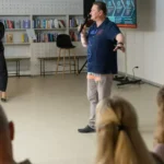 Жінка і чоловік з мікрофонами виступають перед аудиторією біля полиць з книгами