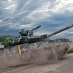 Український танк їде ґрунтовою дорогою і здіймає хмару пилу