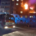 Пожежна машина біля охопленої полумям багатоповерхівки вночі