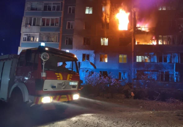 Пожежна машина біля охопленої полумям багатоповерхівки вночі