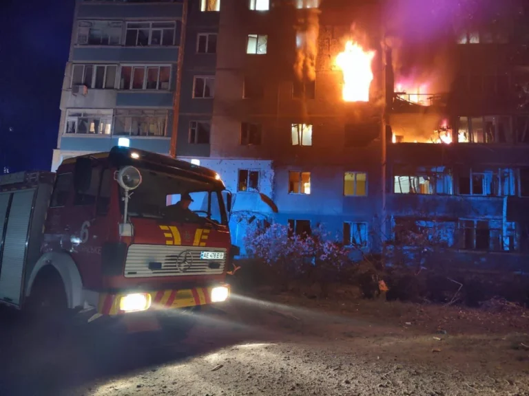 Пожежна машина біля охопленої полумям багатоповерхівки вночі