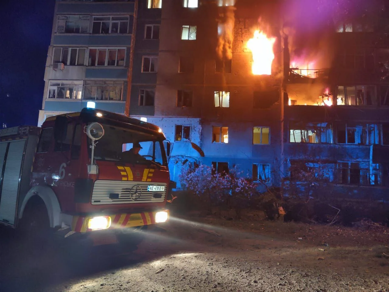 Пожежна машина біля охопленої полумям багатоповерхівки вночі