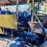 Пошкоджений жовтий рейсовий автобус із розірваним передком і уламками на бруківці