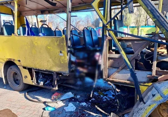 Пошкоджений жовтий рейсовий автобус із розірваним передком і уламками на бруківці