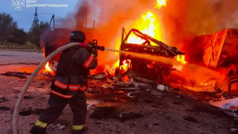 Рятувальник у касці гасить сильну пожежу на палаючій техніці серед уламків