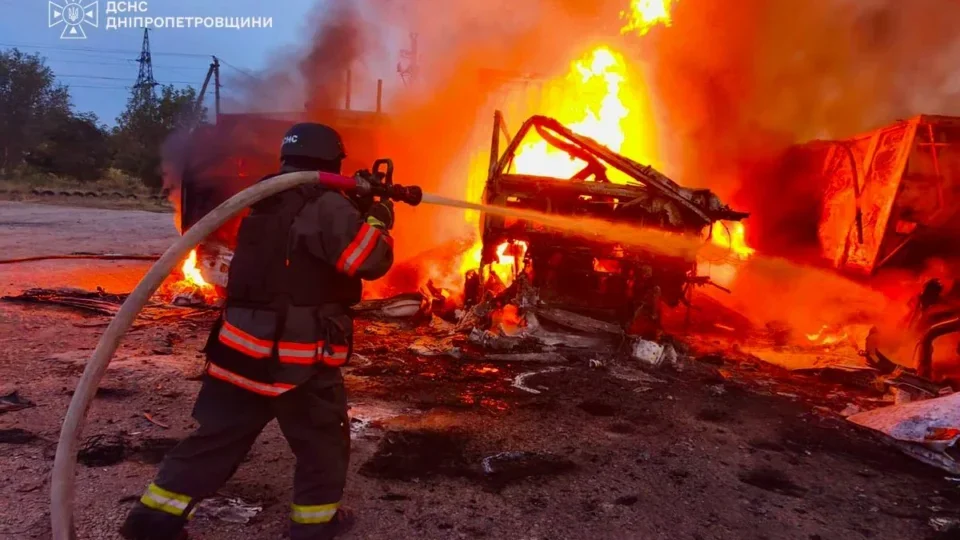Рятувальник у касці гасить сильну пожежу на палаючій техніці серед уламків