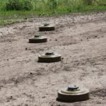 Чотири протитанкові міни викладені на ґрунтовій дорозі біля трави