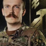 Денис Прокопенко в камуфляжі Нацгвардії на тлі золотої емблеми Азову