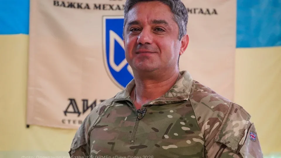 Медик Хосро в камуфляжі на тлі банера бригади Дике Поле